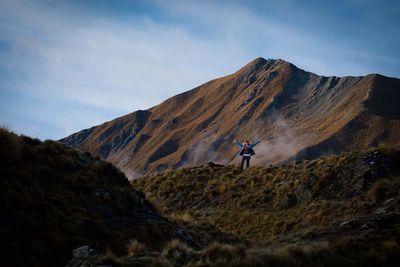 Woman with raised arms against mountain