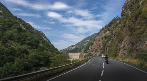Cars on road by mountain against sky