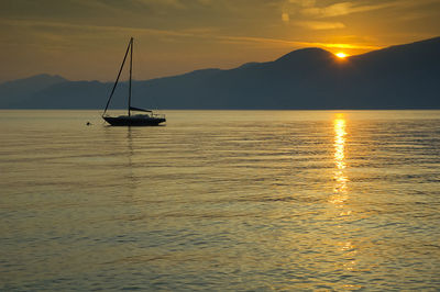 Silhouette sailboat in sea against sky during sunset