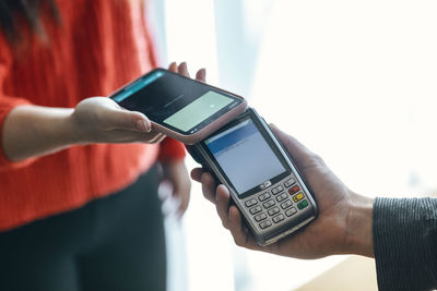 Hand of woman making contactless payment through mobile phone