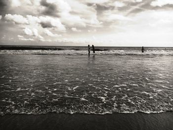 Silhouette people standing on beach against sky