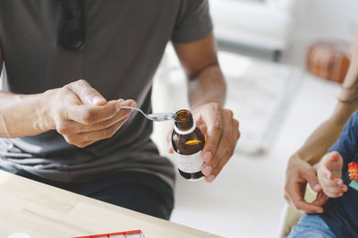 Father giving medicine to son sitting with mother at home