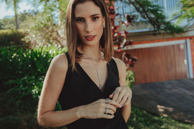 Portrait of beautiful young woman standing against plants