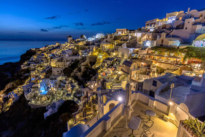 Illuminated houses by sea at santorini during night