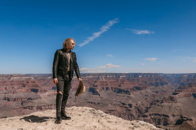 Man standing on rock against sky