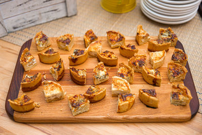 Slices of baked quiche with cheese and mushroom on a wooden board