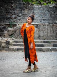 Full length of young woman wearing traditional clothing standing by old wall