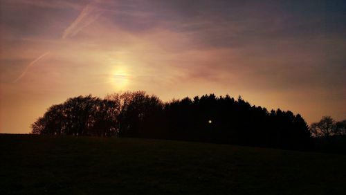 Silhouette of trees on landscape at sunset