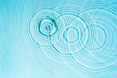 Circles and waves on blue water in sunlight