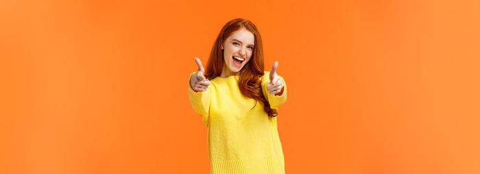 Low angle view of young woman wearing hat against yellow background