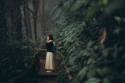 Woman standing by trees in forest