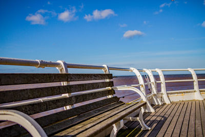 Metallic railing by sea against blue sky