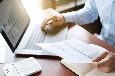 Midsection of man using laptop on table