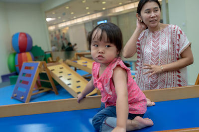 Mother standing by cute daughter playing indoors
