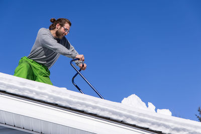 Low angle view of man against clear blue sky