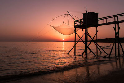 Traditional wooden fishing hut on stilts called fishery by the ocean with a beautiful sunset