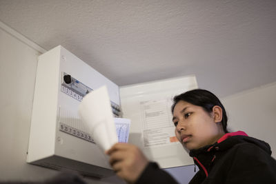 Woman checking electric fuse box