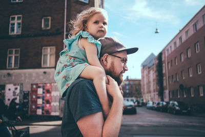 Full length of father and daughter standing on street in city