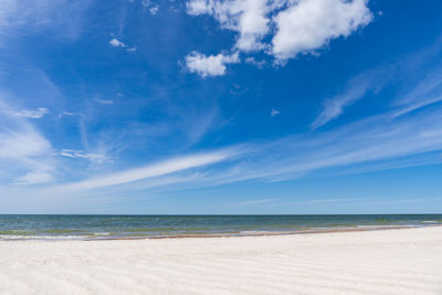 Scenic view of empty beach against blue sky with clouds