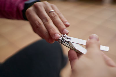 Anonymous person cutting nails with clipper person