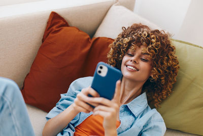 Midsection of woman using mobile phone while sitting on sofa at home