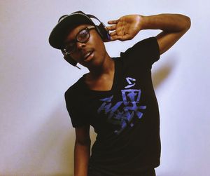 Portrait of happy young man wearing headphones listening music against wall