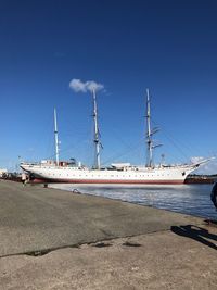 Sailboats moored at harbor against blue sky