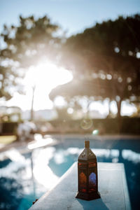 Close-up of beer bottle on table against sky on sunny day