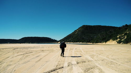 Rear view of man walking on landscape against sky