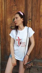 Young woman looking away while standing against door