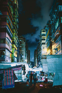 People on street amidst buildings in city at night