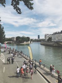 People by river in city against sky