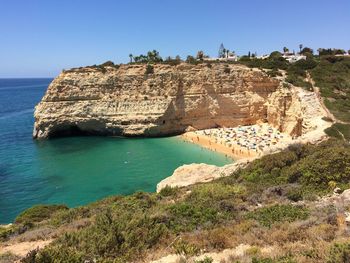 High angle view of cliff by sea against clear sky