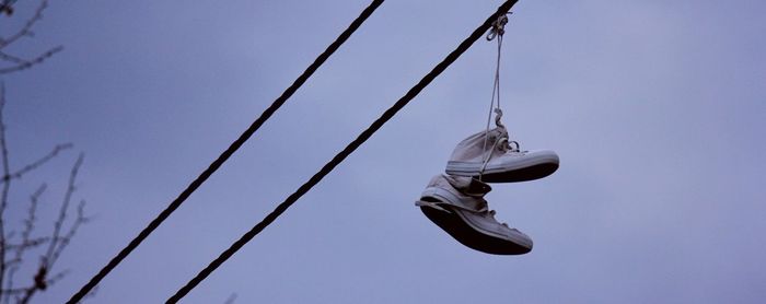 Low angle view of shoes hanging against clear blue sky