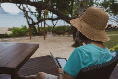 Rear view of woman using mobile phone sitting outdoors