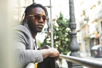 Portrait of young man standing by railing