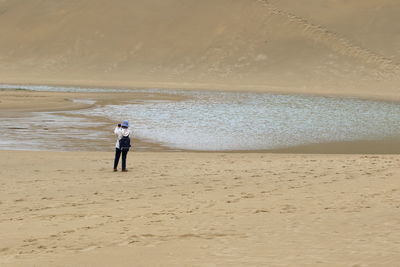 Full length of man standing on beach against sky