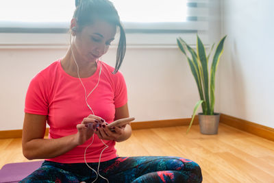 Smiling woman listening music while sitting on floor at home