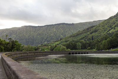 Scenic view of river by mountains against sky