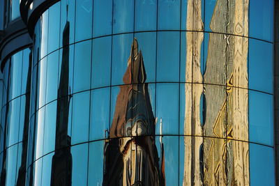 Low angle view of glass building against blue sky
