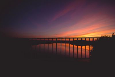 Silhouette pier over lake against romantic sky at sunset