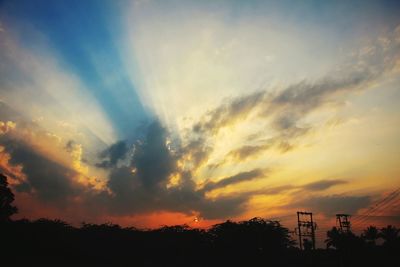 Low angle view of silhouette trees against dramatic sky