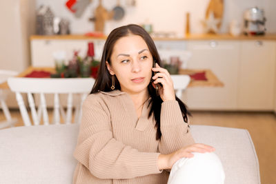 Cute woman using smartphone to call family on christmas eve. talks to relatives