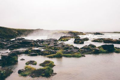 Scenic view of river flowing through rocks against clear sky