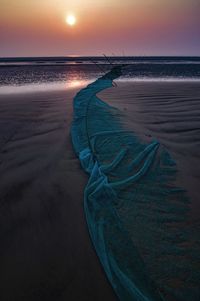 Scenic view of sea against sky at sunset and fishing nets