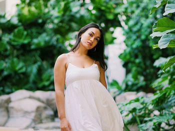 Portrait of young woman standing against trees