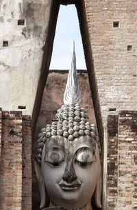 Statue of buddha against wall of building