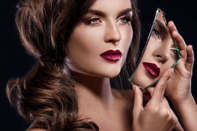 Close-up of young woman with make-up against black background
