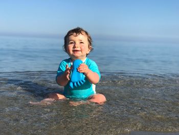 Baby boy with toy sitting at beach