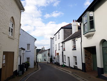 An empty street amidst buildings and under a blue sky with clouds in totnes, devon.